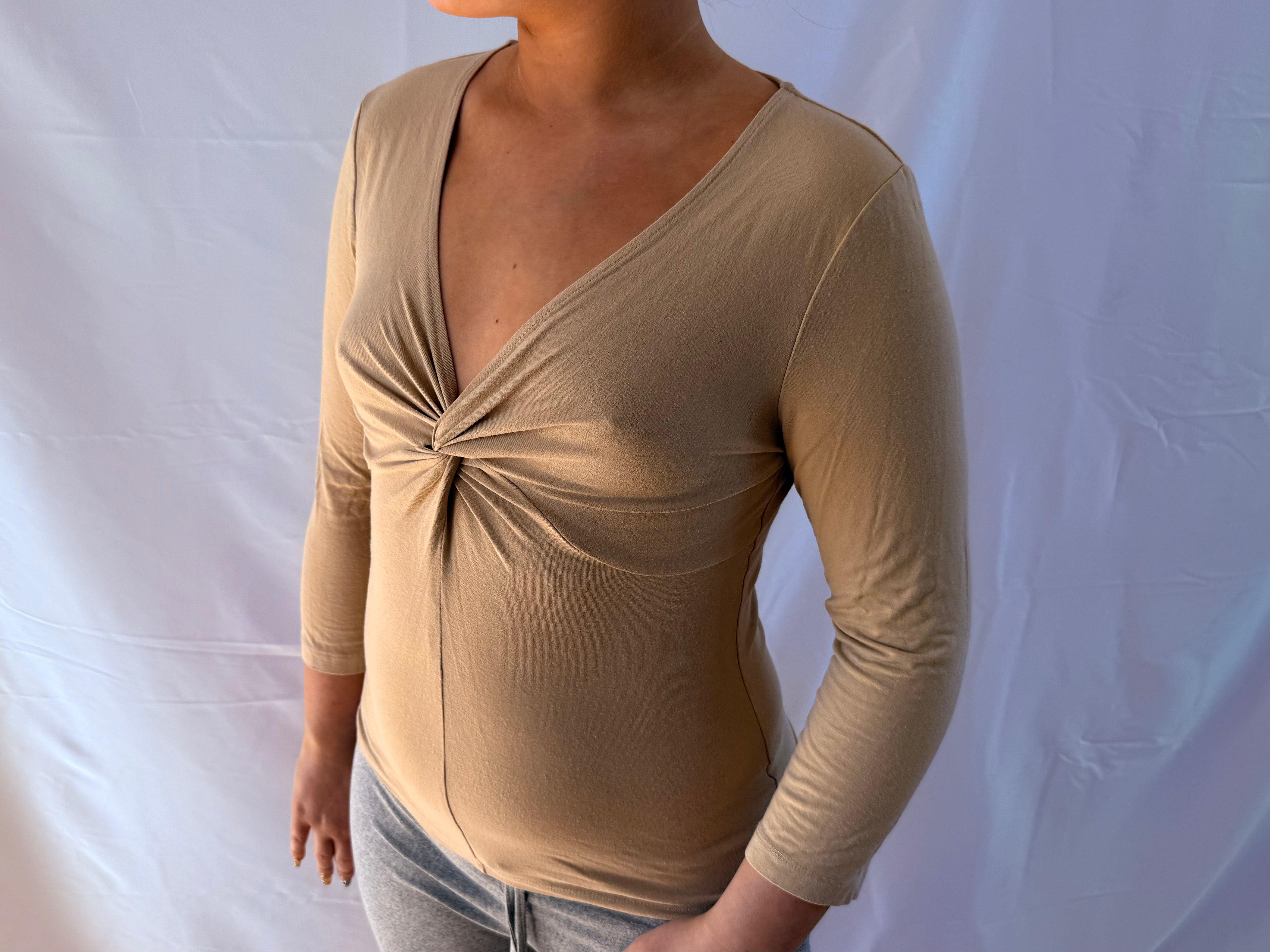 Beige trekvartærmet top med v udskæring.